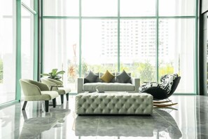 A modern living room with a sofa, chairs, and a glass wall.