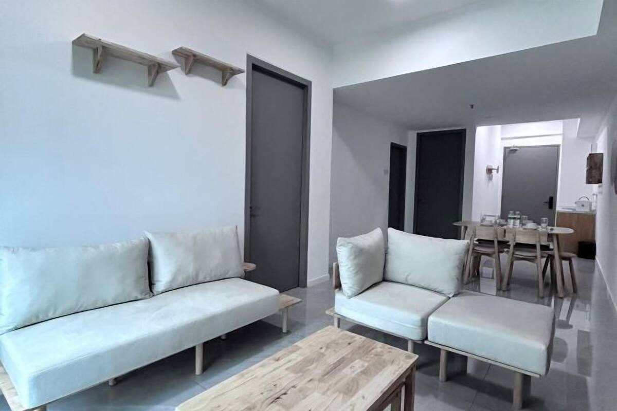 A living room with a sofa, a coffee table, and a dining area with chairs and a table.