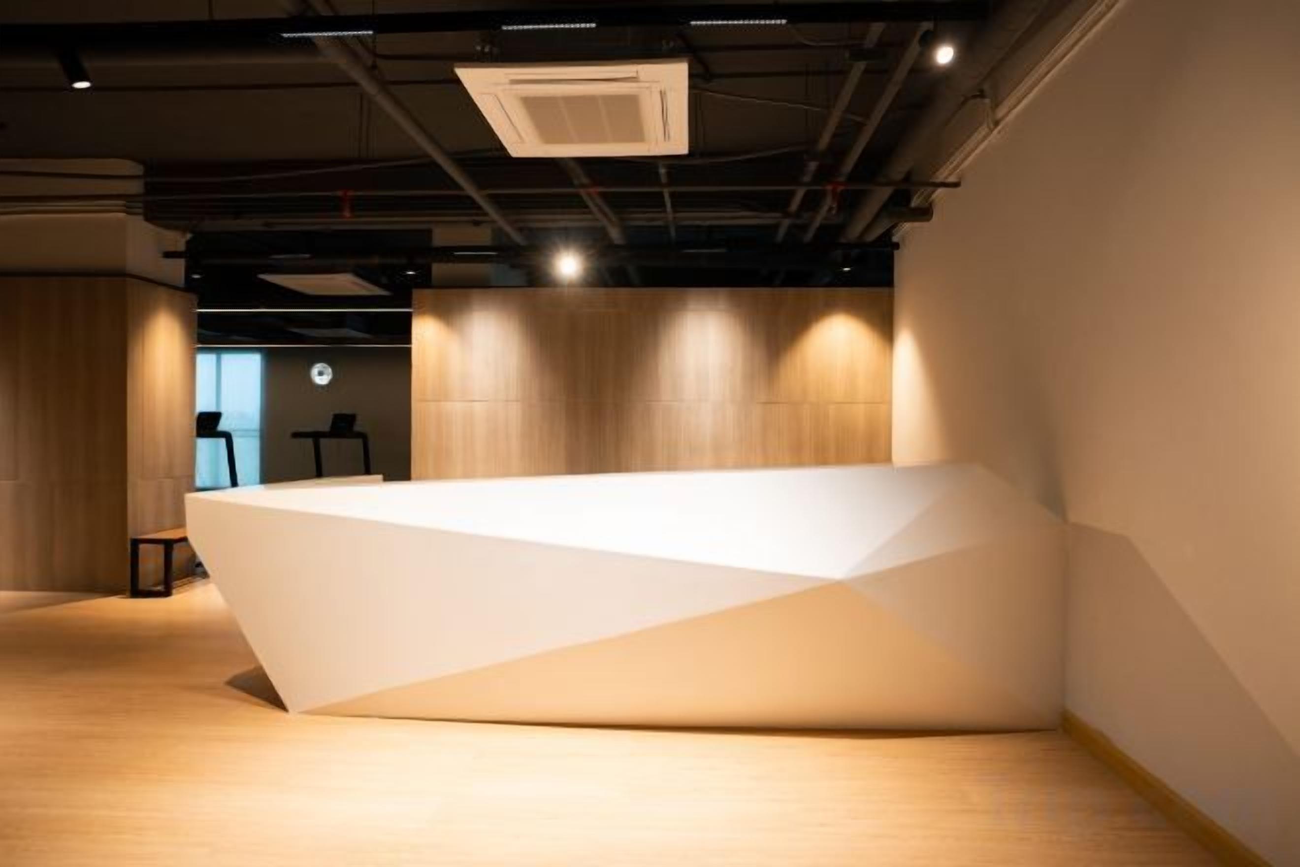 A modern reception desk with a geometric design, located in a room with wooden flooring and walls.