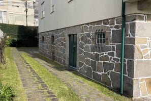 A stone facade with a green door, a paved pathway, and a small garden area. - Imaculada Home Royal - Centro de Braga, Historico (Braga)