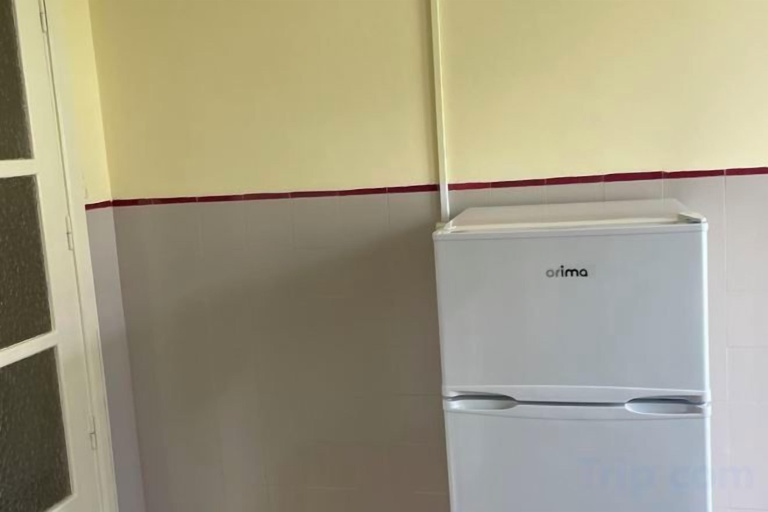 Un refrigerador blanco con el nombre de marca 'arima' en una cocina.