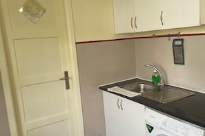 A compact kitchen with a sink, a washing machine, and cabinets. - Imaculada Home Royal - Centro de Braga, Historico (Braga)
