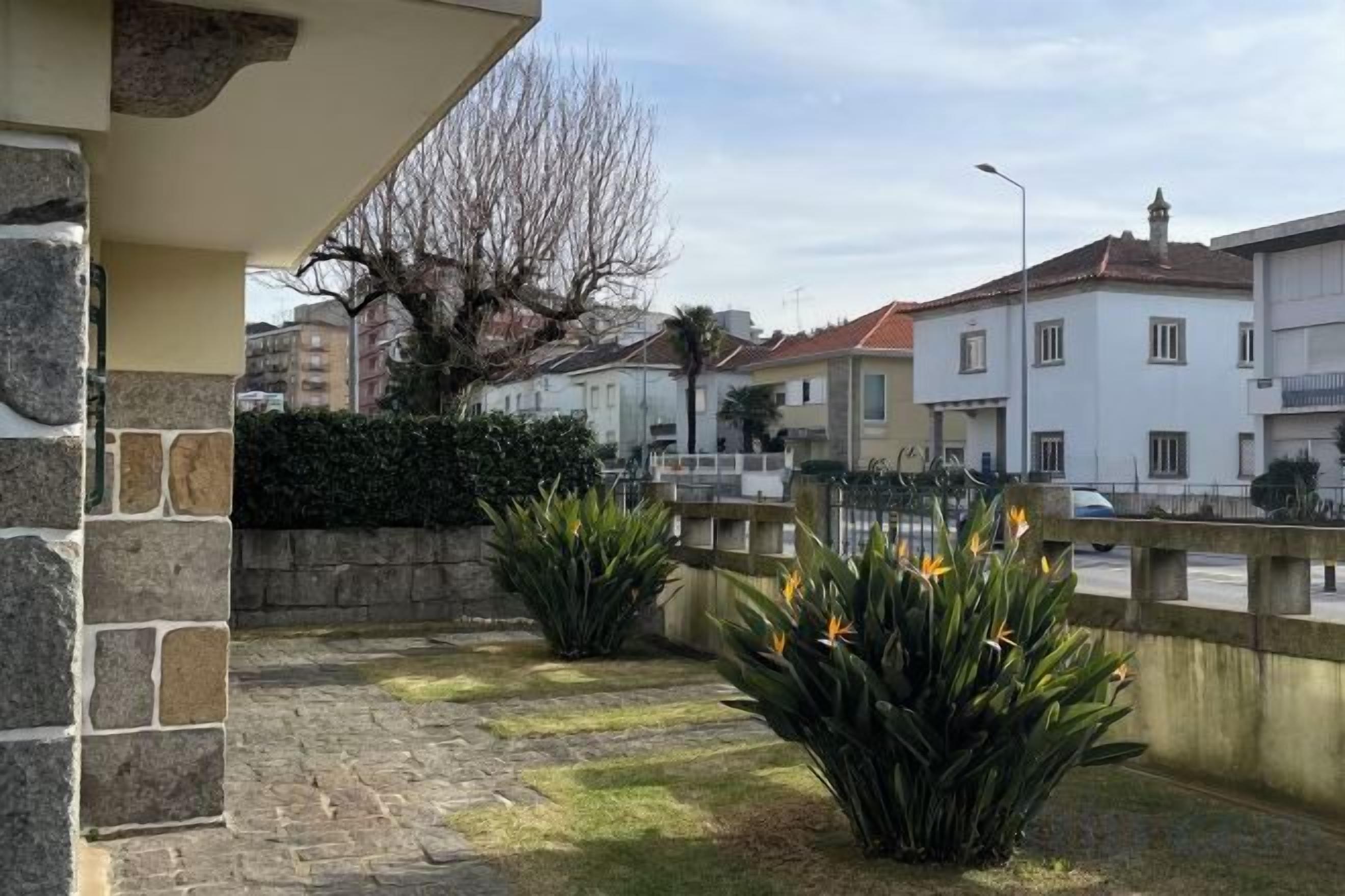 A residential area with a paved patio, stone wall, and a street view.