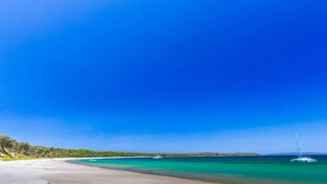 A beach with clear turquoise waters, a sandy shore, and a distant tree line. - Beachfront Escape Relaxing Getaway in Batehaven (Batehaven)