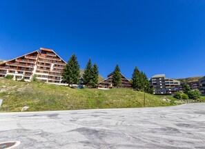 A modern hotel with multiple buildings, each featuring balconies and a mountainous backdrop.