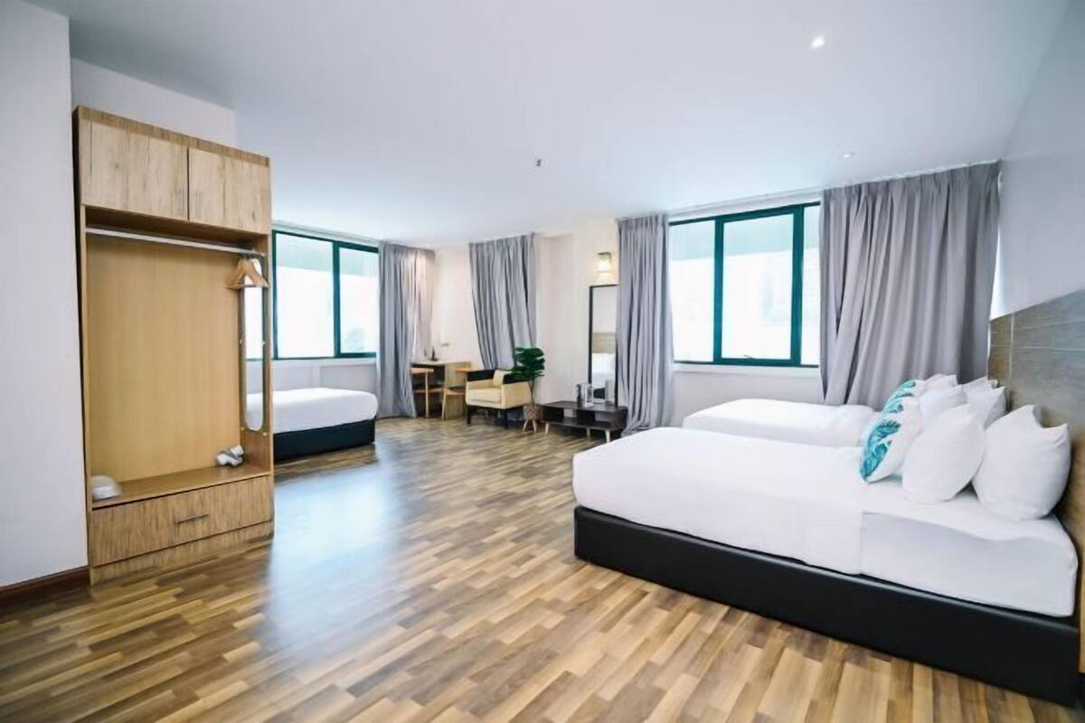A modern hotel room with a wooden floor, a large bed, a desk, and a wardrobe.
