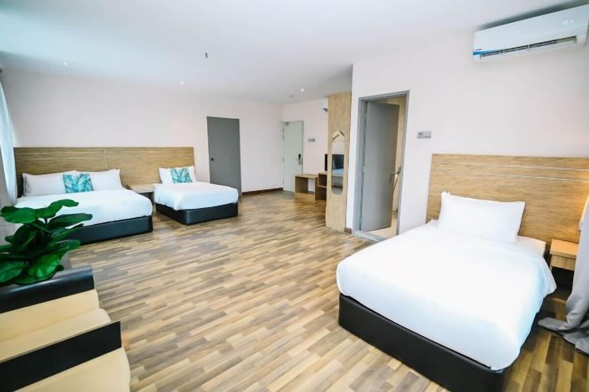 A hotel room with two beds, a wooden floor, and a small seating area.