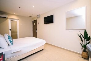 A hotel room with a bed, a TV mounted on the wall, a door, and a potted plant. - Kingston Hotel 1 @ Bukit Bintang (Kuala Lumpur)
