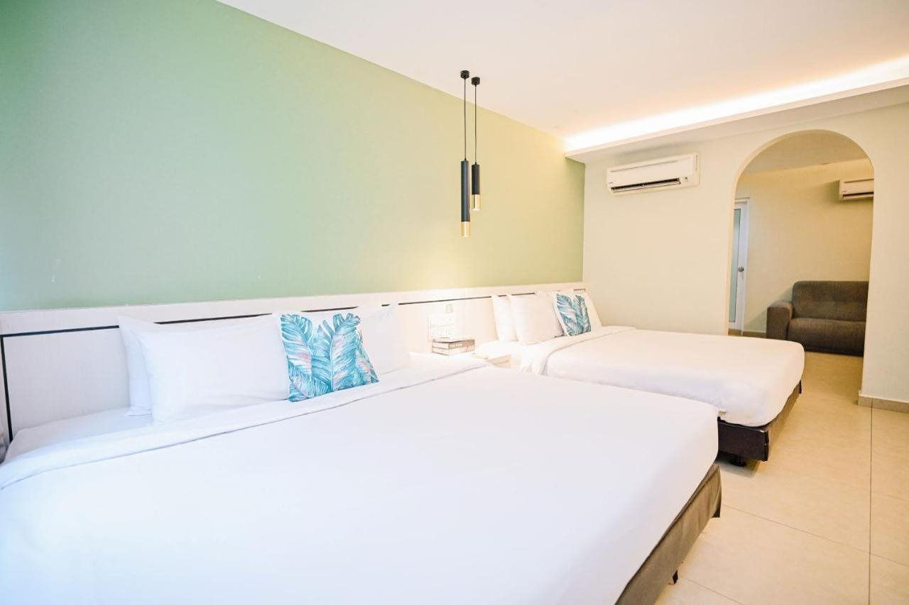 Habitación de hotel con dos camas, una mesita, una silla y un arco de entrada.