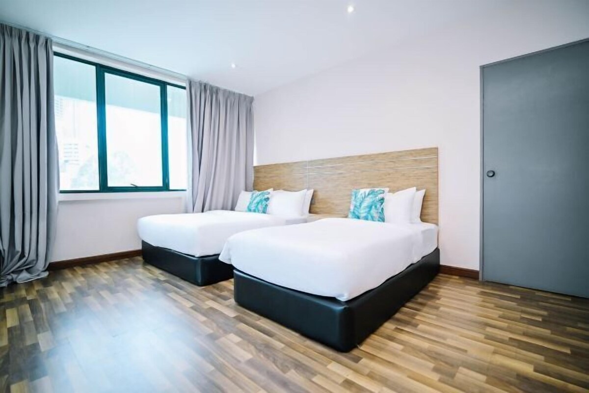 A hotel room with two beds, a large window, and a door.