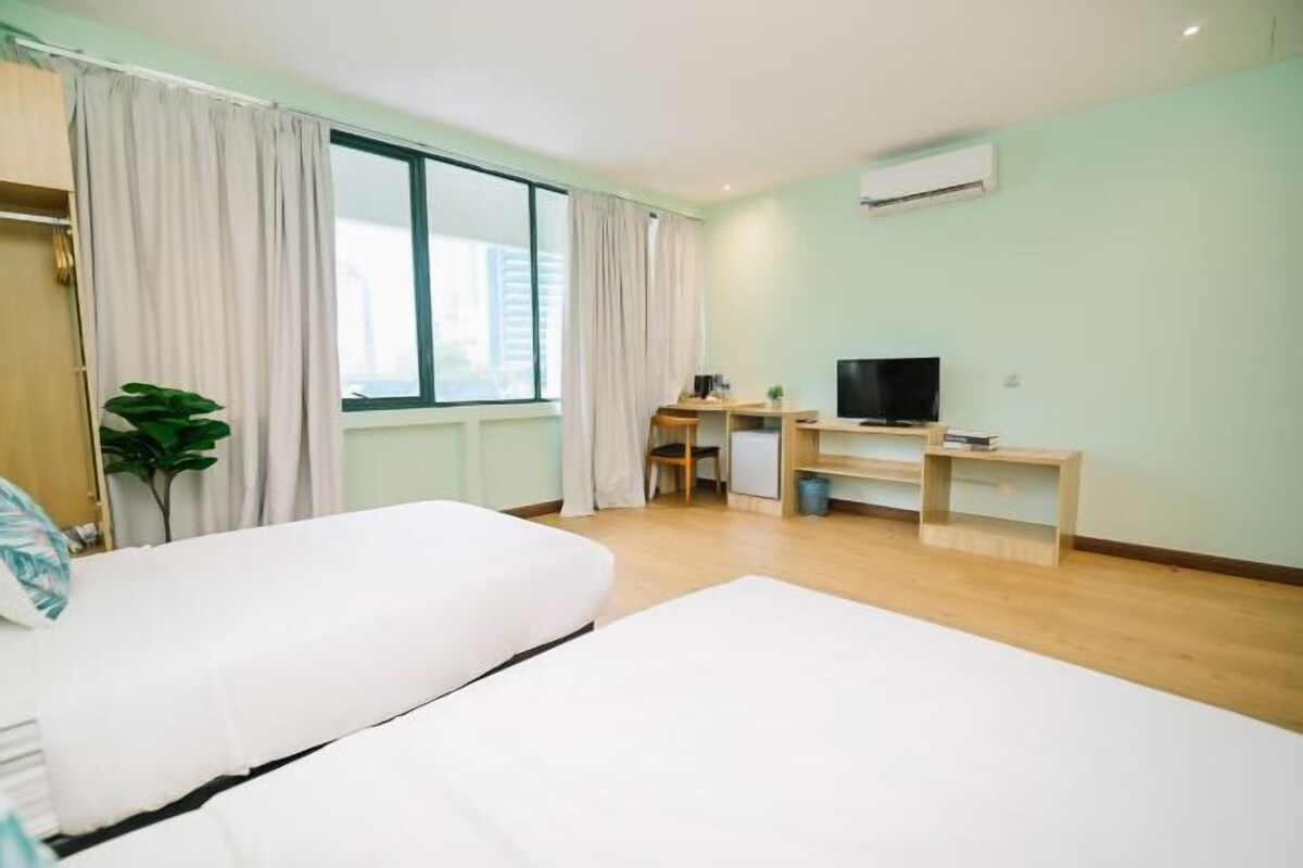A hotel room with a bed, a desk, a television, and a window with curtains.