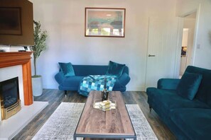 A living room with a fireplace, a blue sofa, a coffee table, and a painting on the wall.
