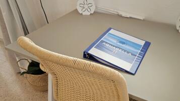 A small table with a blue book titled "Aquabella II" and two decorative white objects with floral designs.