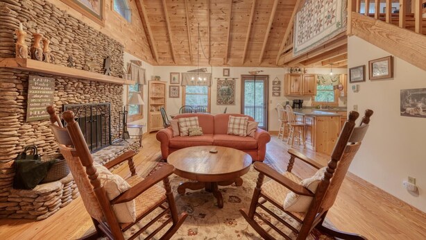 Un intérieur de chalet chaleureux avec une cheminée en pierre, des meubles en bois et un coin cuisine.