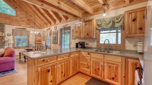 Une cuisine spacieuse avec des meubles en bois, un grand îlot central et un mur en pierre.