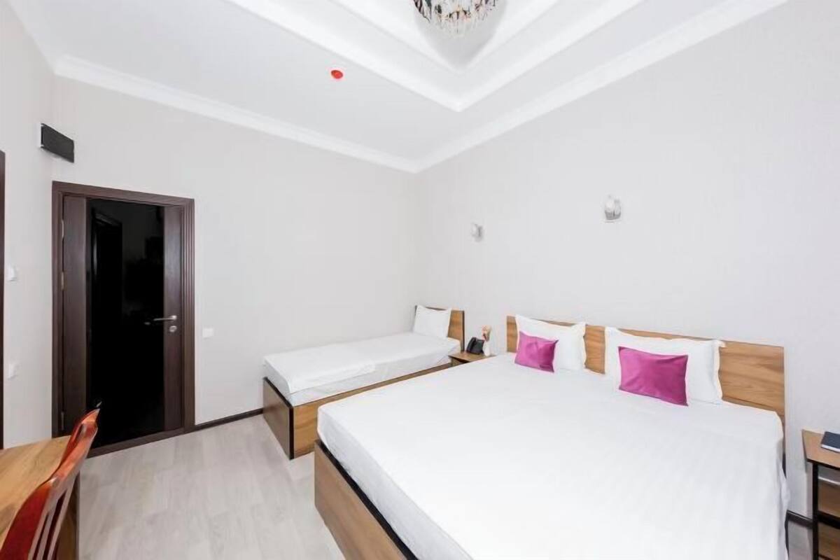A hotel room with a large bed, a smaller bed, a desk, and a chair.