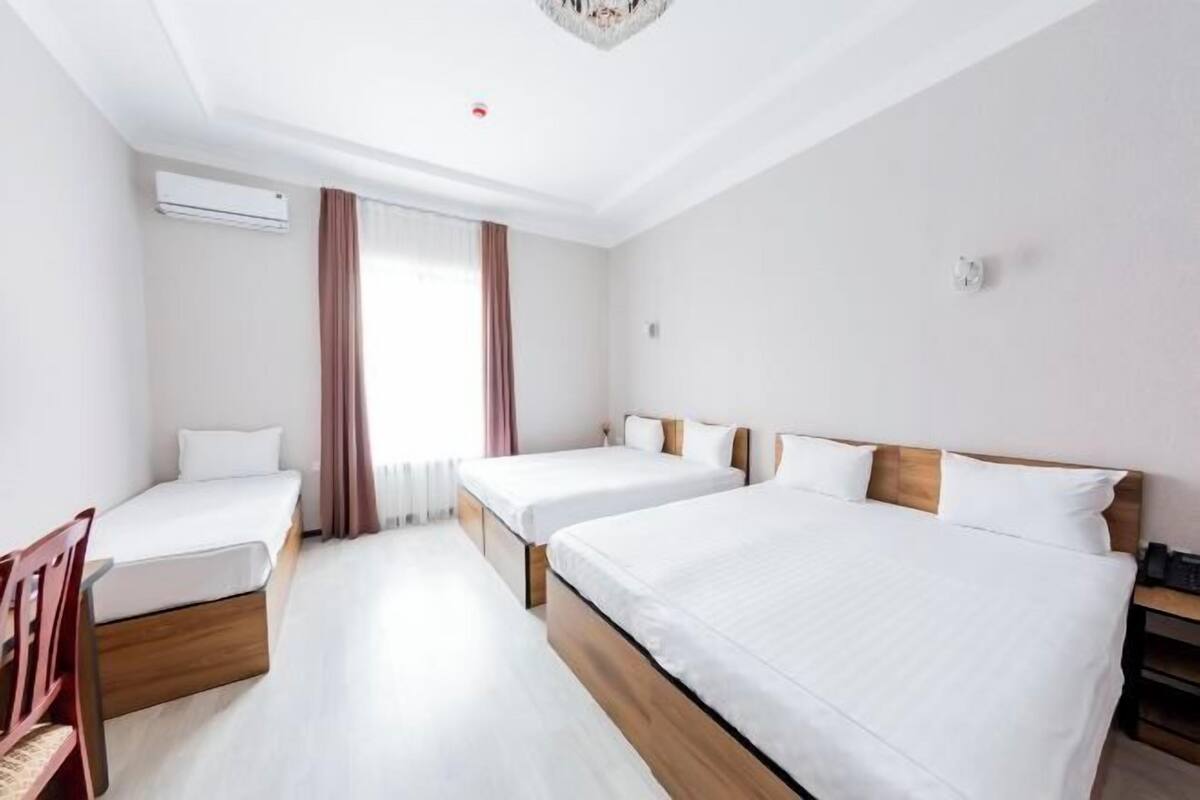A hotel room with two single beds, a wooden headboard, a desk, and a chair.