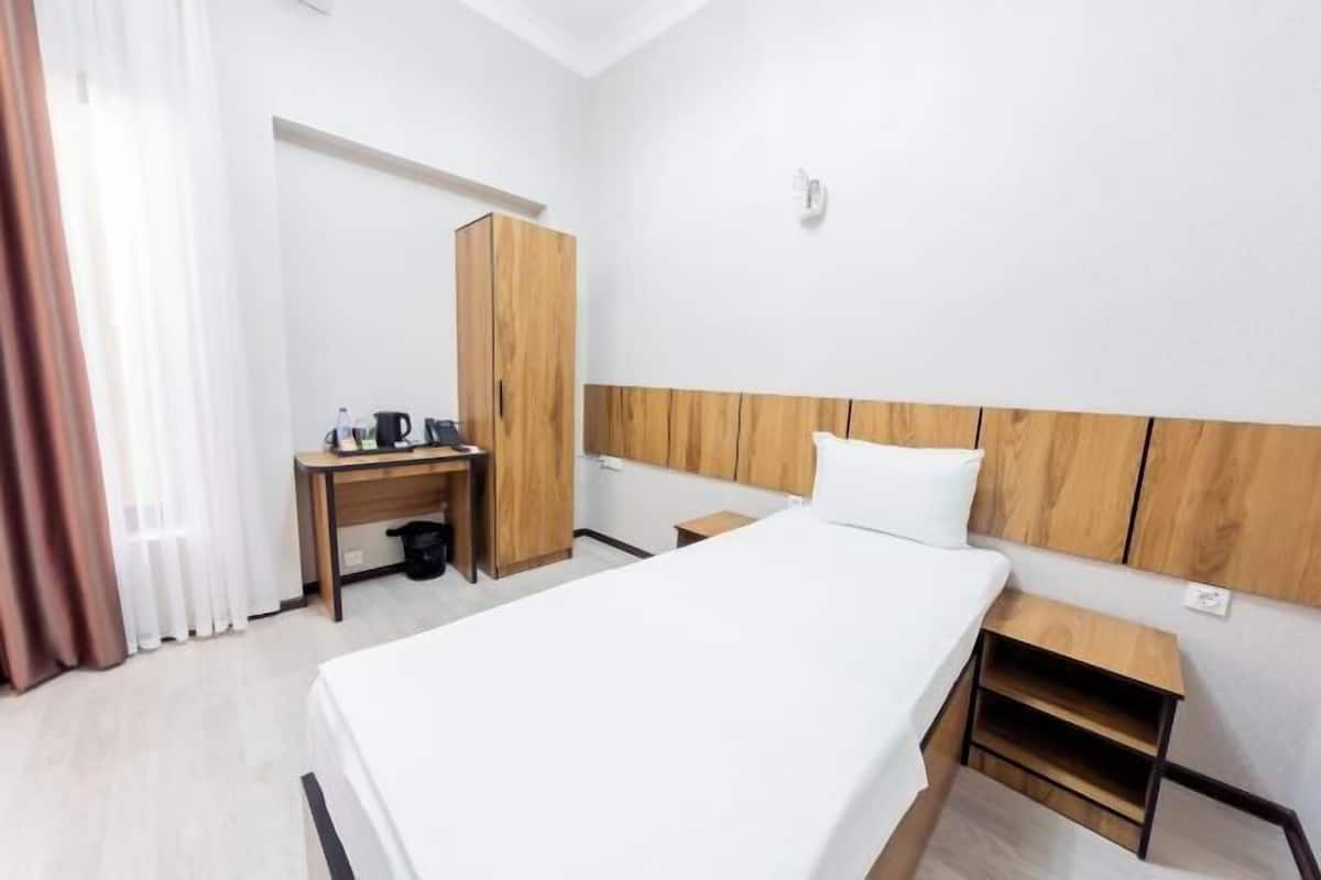 A hotel room with a bed, a desk, a wardrobe, and a small table.