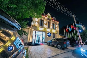 A hotel entrance with a driveway and parked cars. - Centrum Hotel Tashkent (Tashkent)
