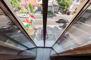 Vista desde una ventana con una calle despejada, que incluye autos estacionados y edificios.