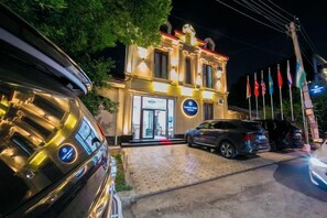 A building with a prominent entrance, a paved driveway, and multiple flags. - Centrum Hotel Tashkent (Tashkent)