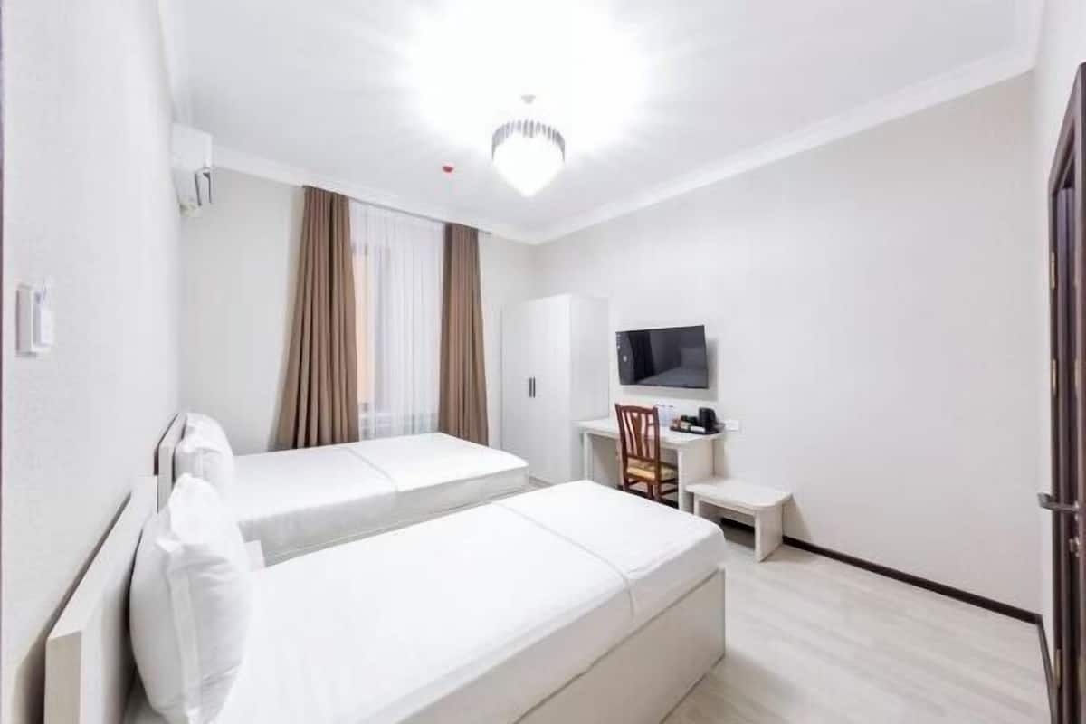 A hotel room with a bed, a desk, a chair, a television, and a wardrobe.