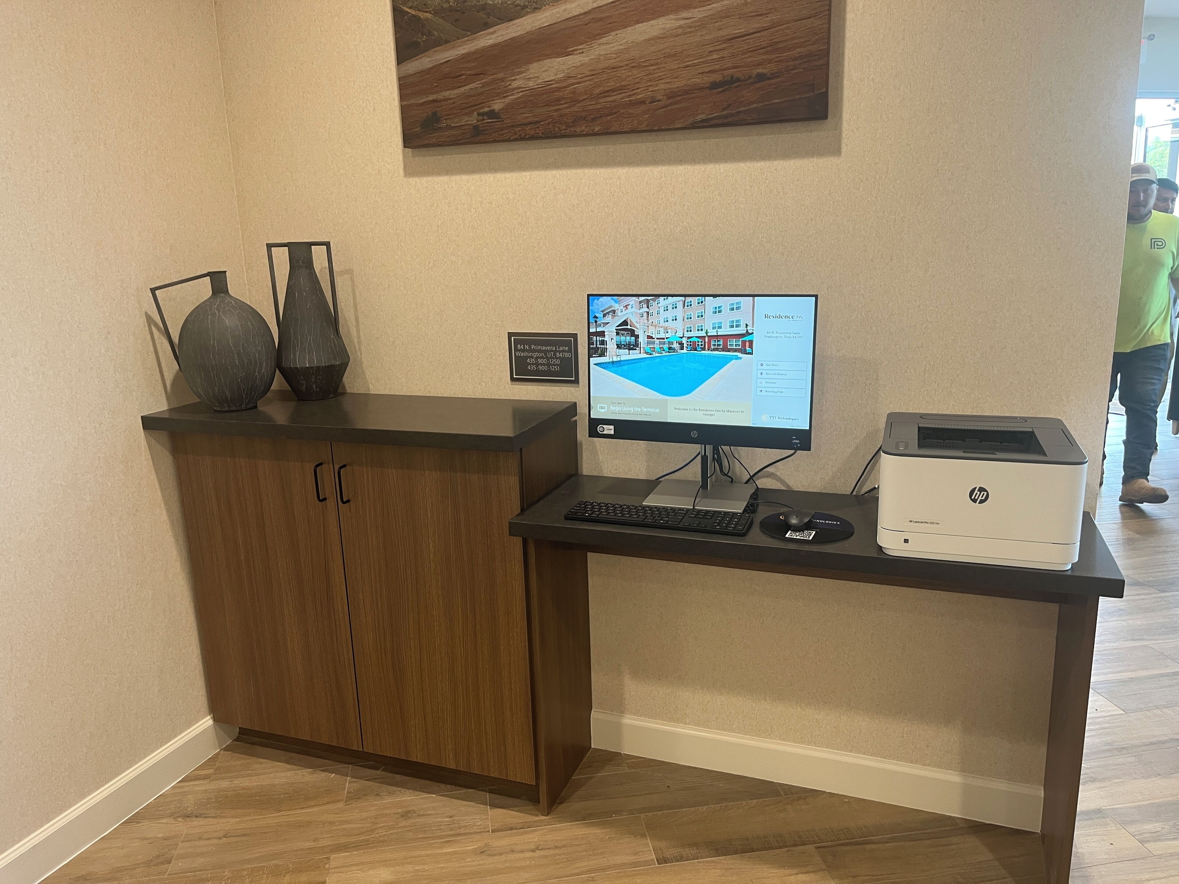 A reception desk with a computer, HP printer, and a sign indicating the address.