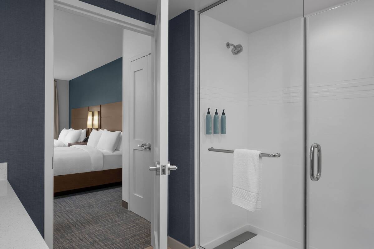 Habitación de hotel con cama, ducha y artículos de aseo en la pared.