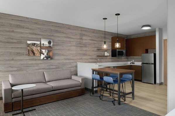 A modern kitchen with a built-in microwave, a stainless steel refrigerator, and a wooden dining table with blue chairs. - Residence Inn By Marriott St. George (Washington)