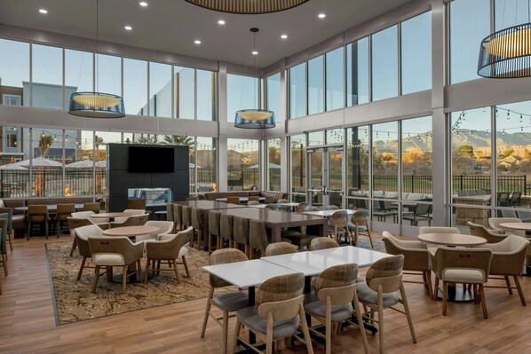 A spacious indoor area with large windows, multiple seating arrangements, and a central table.