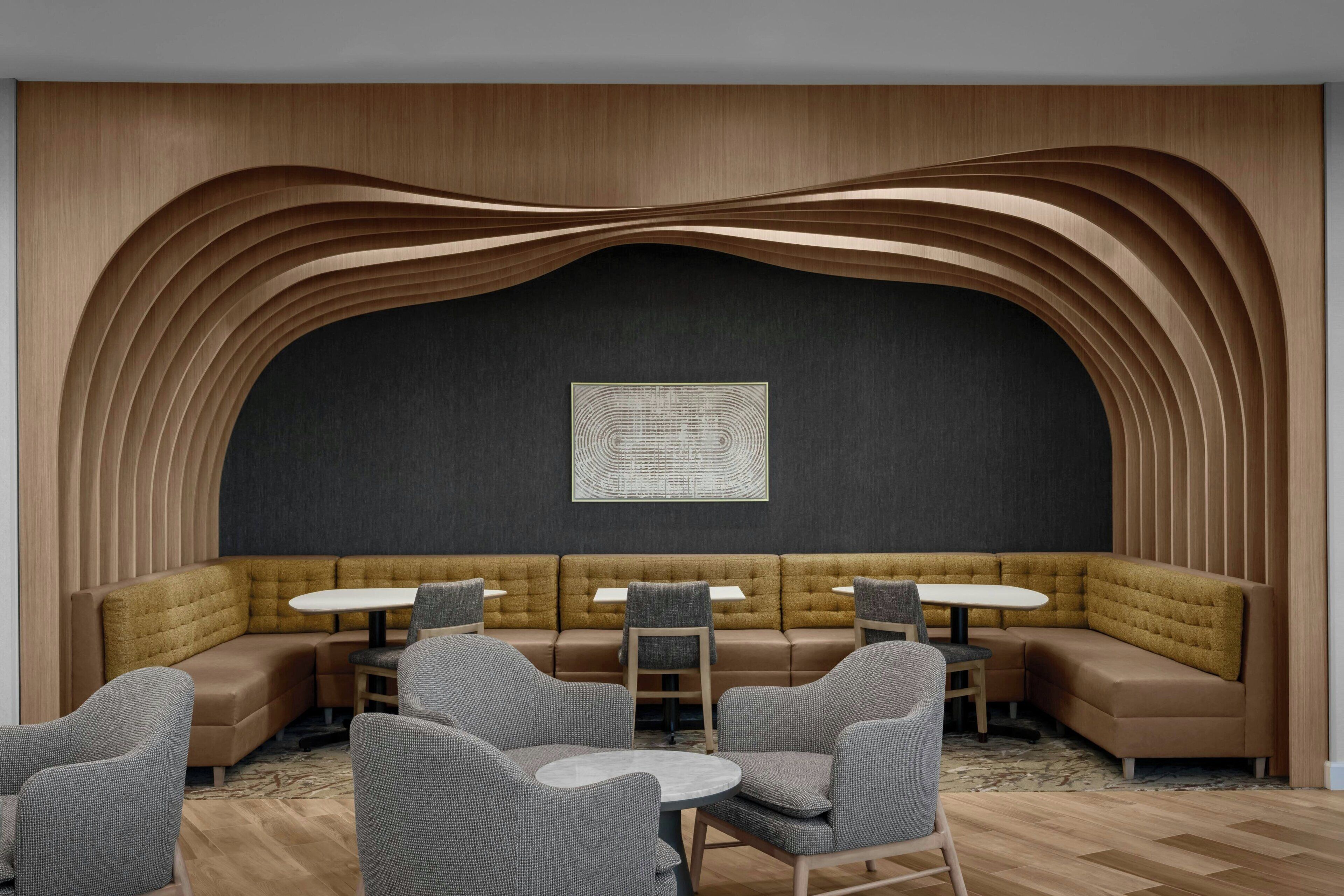 A modern lounge area with a curved wooden wall, a central seating area, and a patterned wall art piece.