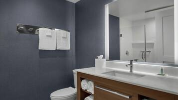 A modern bathroom with a white sink, a large mirror, and a towel rack.