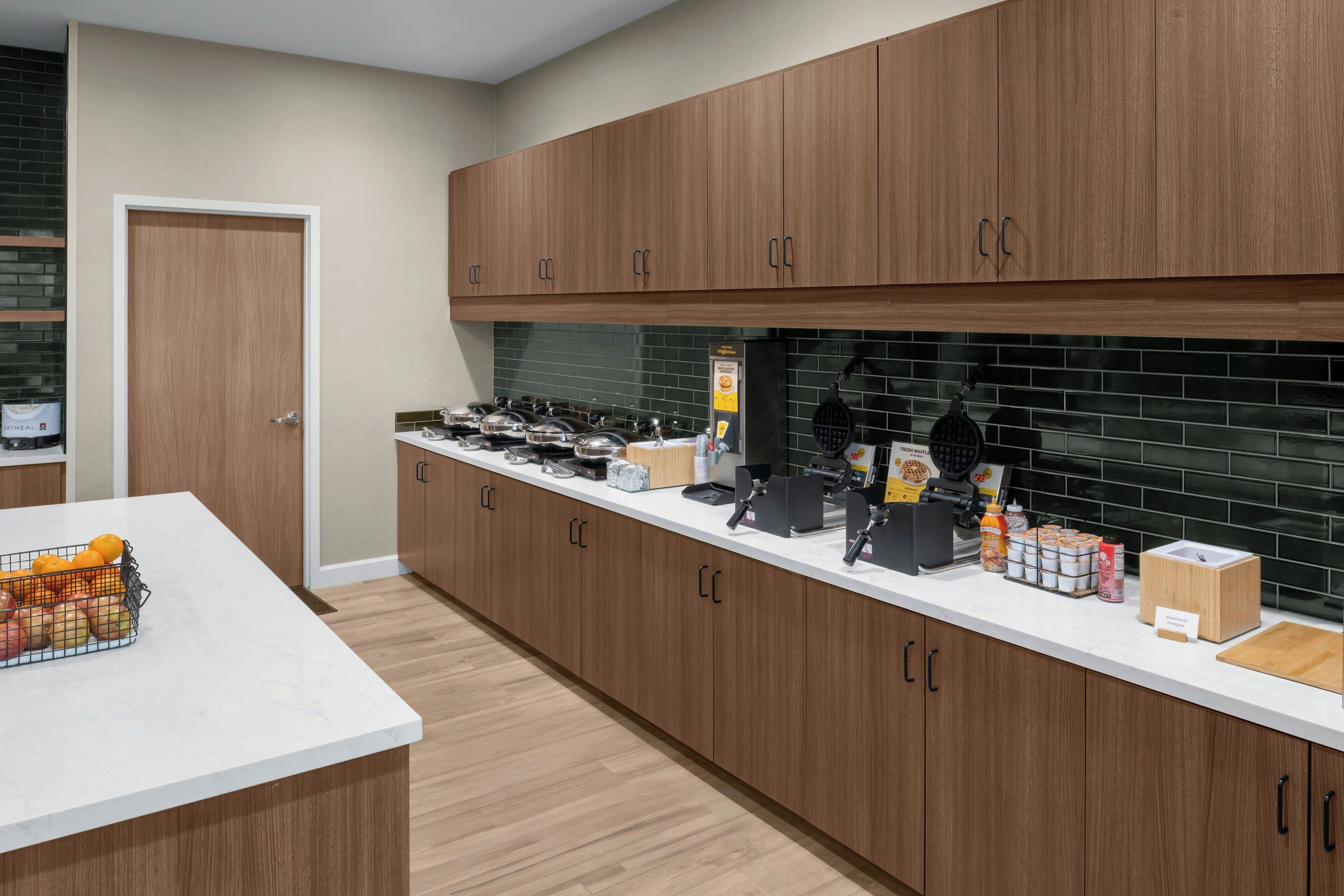 Una cocina moderna con armarios de madera, encimera blanca y varios electrodomésticos.
