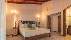 A bedroom with a wooden bed, two bedside tables, and a nightstand. - Hotel and restaurant in Bequia (Bequia)