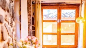 Un comedor acogedor con paredes de piedra, una mesa de madera y sillas. Hay cuencos con comida y un jarrón de flores sobre la mesa.
