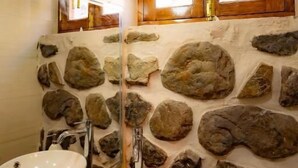 Un baño con dos lavamanos, un espejo, una pared de piedra y una ventana con contraventanas de madera.