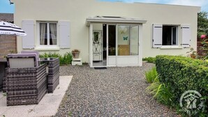 A modern single-story house with a white exterior, a glass door entrance, and a gravel driveway.