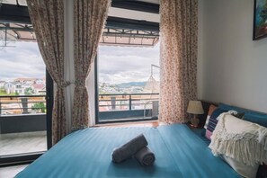 A bedroom with a bed, curtains, a view of the city, and a balcony. - An Phu House Valley View (Dalat)