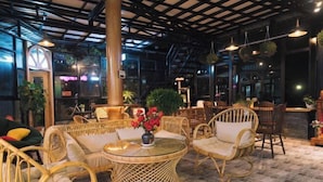 A cozy indoor seating area with wicker furniture, a glass table, and potted plants. - An Phu House Valley View (Dalat)