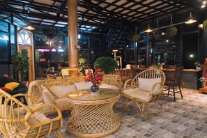 A cozy indoor seating area with wicker furniture, a glass table, and a decorative vase. - An Phu House Valley View (Dalat)