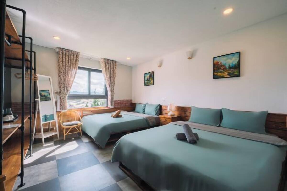 A room with two beds, a desk, a chair, and a window with curtains.