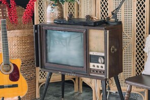 A vintage television set on a stand with a guitar nearby. - An Phu House Valley View (Dalat)
