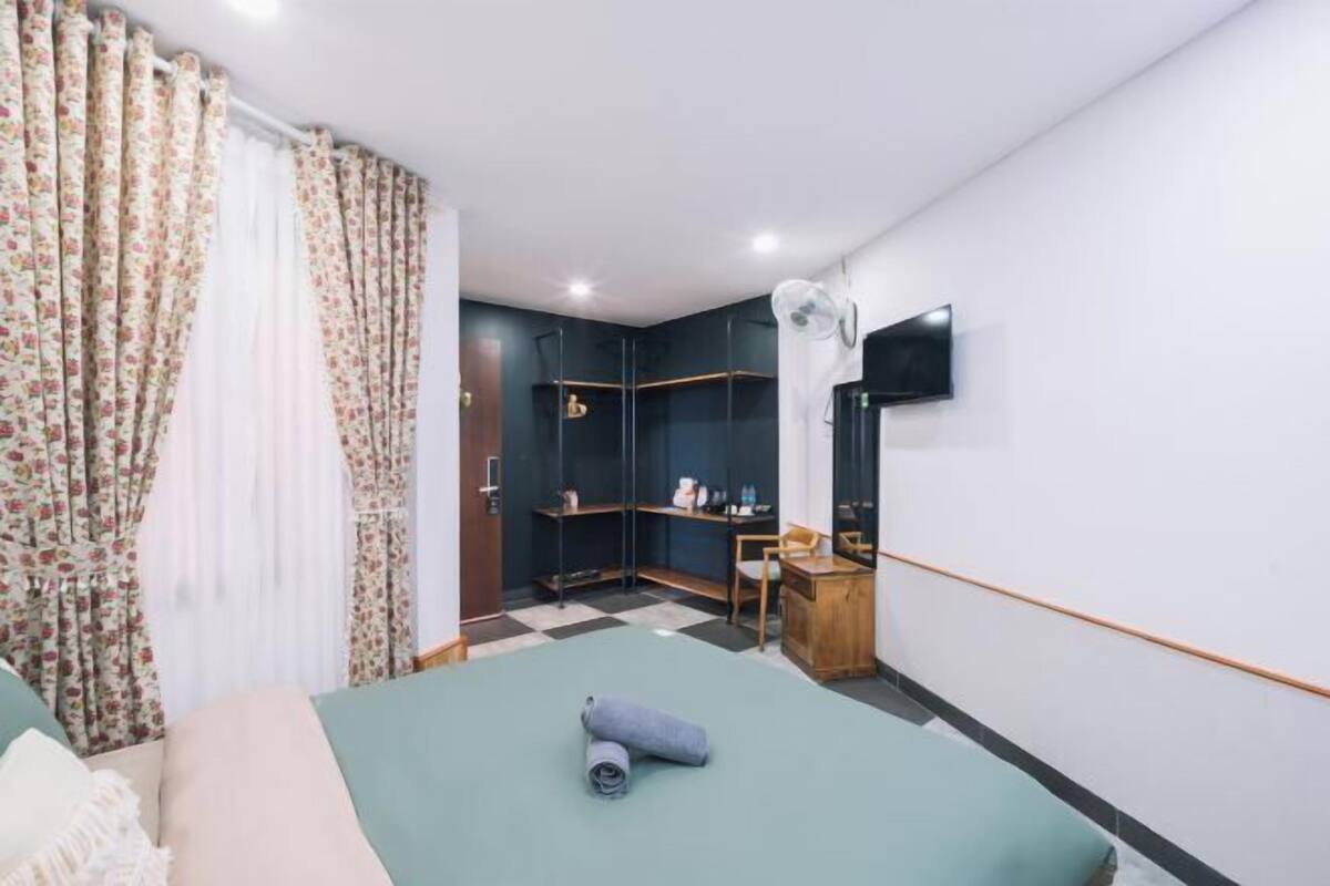 A hotel room with a bed, a desk, a chair, a TV, and a wardrobe.