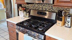 A kitchen with wooden cabinets, a stainless steel stove, a microwave, and a refrigerator.
