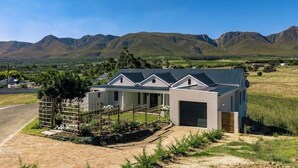 A modern house with a garage, surrounded by a well-maintained garden and a mountainous landscape.