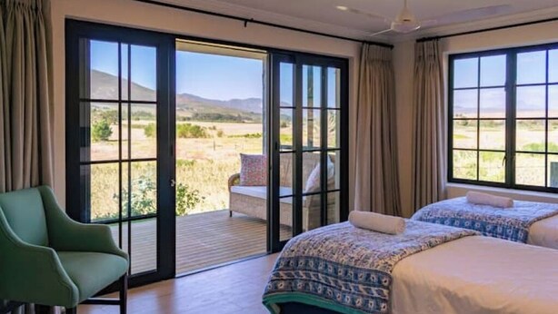 A bedroom with a large bed, a chair, and a sliding glass door leading to an outdoor area.