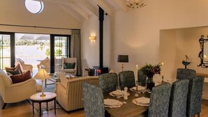 A dining area with a round table set for six, surrounded by six upholstered chairs.