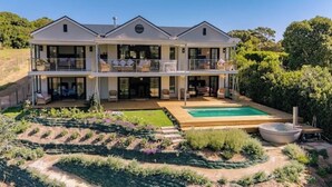 A two-story house with a swimming pool, a covered patio, and a landscaped garden.