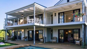 A two-story house with a pool, outdoor seating, and a balcony.