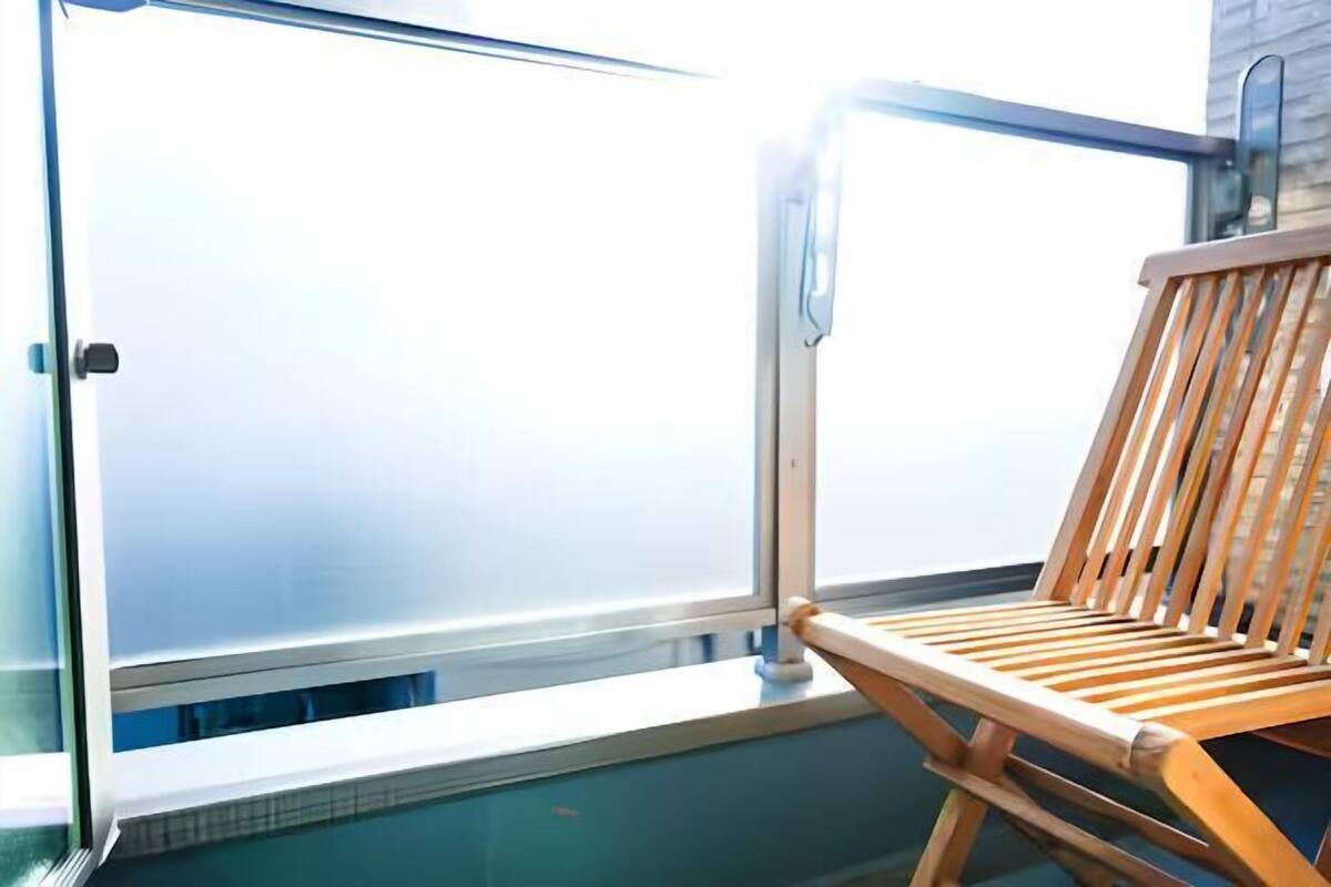 A wooden chair by a window with a view of a building.